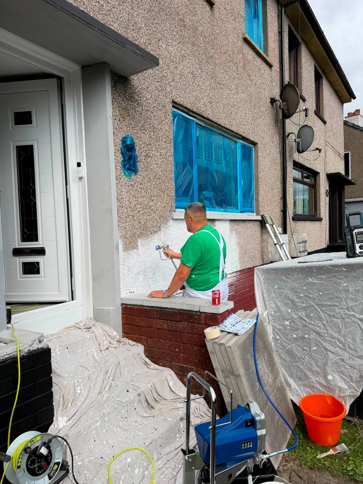 Kev spray painting an exterior wall with professional equipment